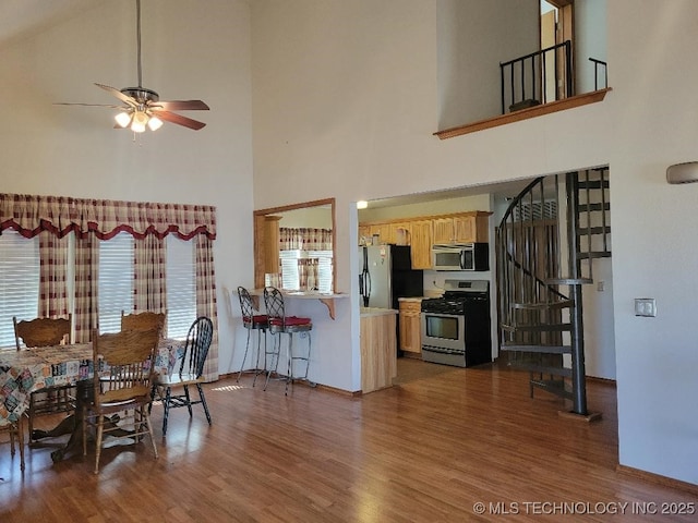 dining area with ceiling fan, baseboards, dark wood-style floors, and stairs