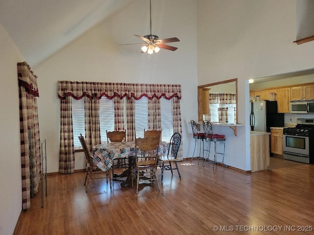 dining space with ceiling fan, wood finished floors, and vaulted ceiling