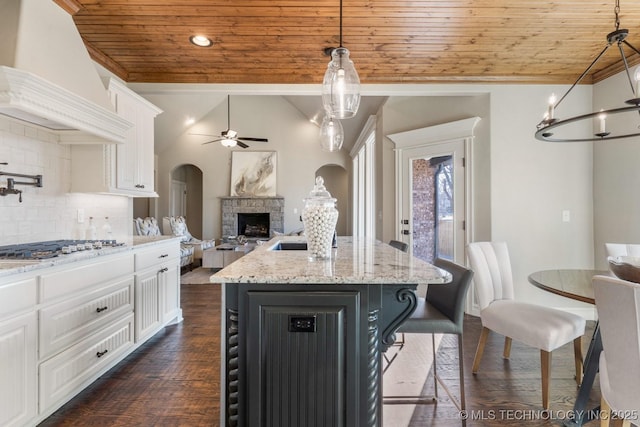 kitchen with white cabinetry, wood ceiling, premium range hood, and arched walkways