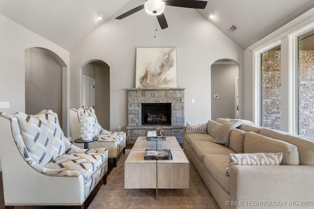 living area with a ceiling fan, a fireplace, visible vents, and high vaulted ceiling