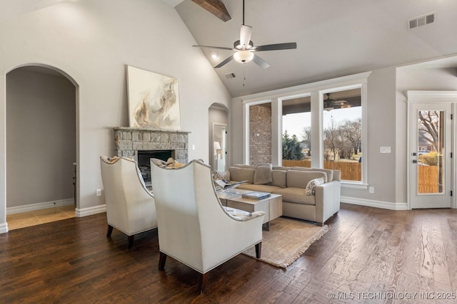 living room featuring visible vents, arched walkways, wood finished floors, and a fireplace