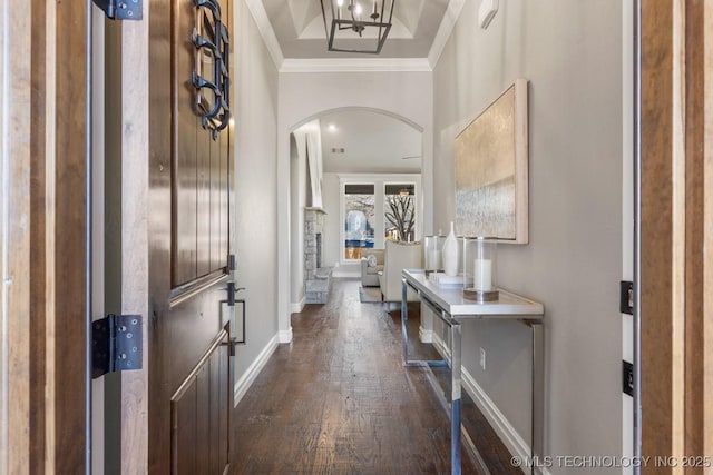 entrance foyer featuring arched walkways, crown molding, dark wood-type flooring, and baseboards