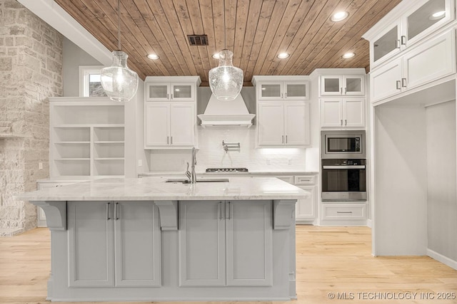 kitchen with premium range hood, a center island with sink, wooden ceiling, stainless steel appliances, and a sink