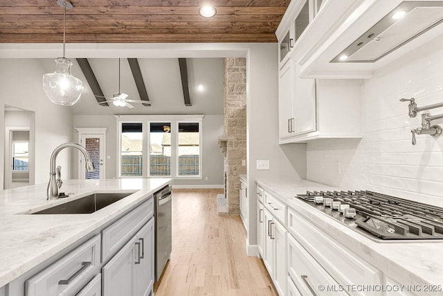 kitchen featuring vaulted ceiling with beams, custom range hood, appliances with stainless steel finishes, white cabinets, and a sink