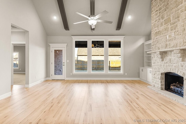 unfurnished living room featuring baseboards, beam ceiling, a fireplace, wood finished floors, and a ceiling fan