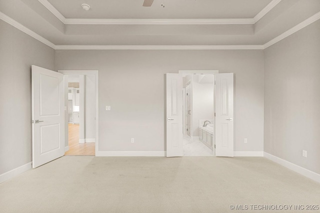 unfurnished bedroom featuring ornamental molding, baseboards, a tray ceiling, and carpet floors