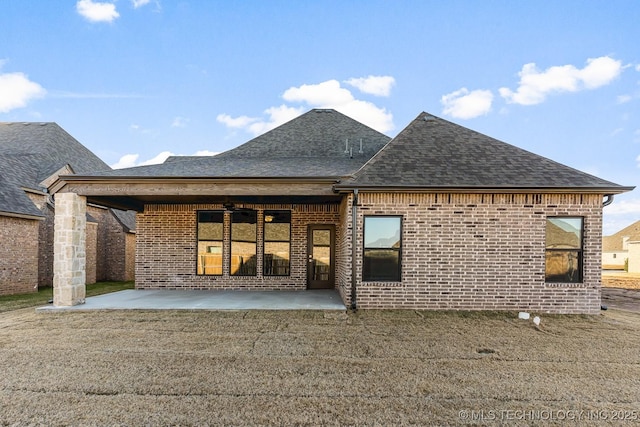 rear view of house featuring brick siding, roof with shingles, ceiling fan, and a patio area