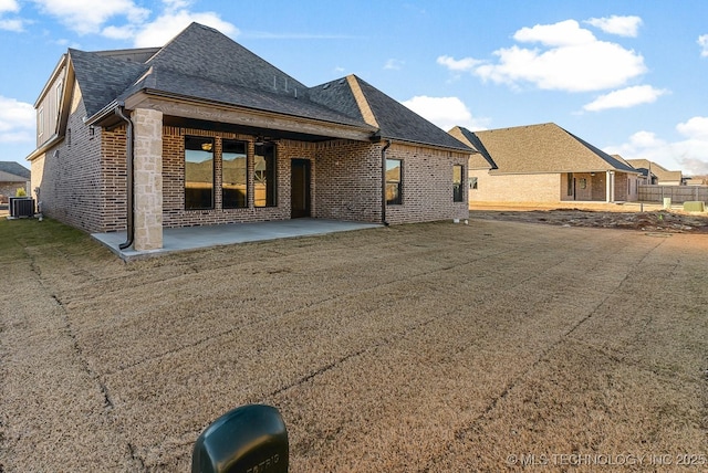 rear view of property with central air condition unit, brick siding, a shingled roof, and a patio area