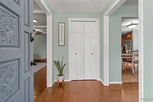 entrance foyer featuring ceiling fan, baseboards, a textured ceiling, and wood finished floors