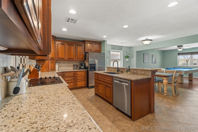 kitchen featuring tasteful backsplash, visible vents, brown cabinets, stainless steel appliances, and a sink