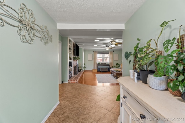 hallway featuring light tile patterned floors, a textured ceiling, and baseboards