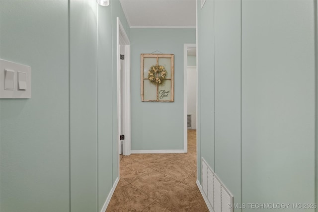 hall with tile patterned floors, visible vents, baseboards, and crown molding