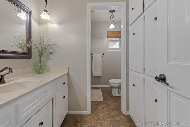 bathroom featuring baseboards, toilet, and vanity