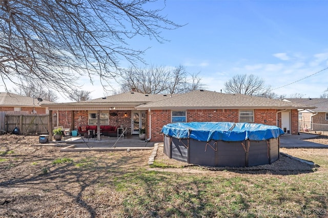 back of property featuring brick siding, a patio area, fence, and a fenced in pool