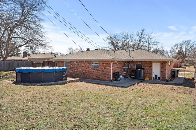 rear view of property featuring a fenced in pool, brick siding, a lawn, and fence