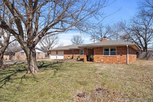 back of house with fence, brick siding, a chimney, and a lawn