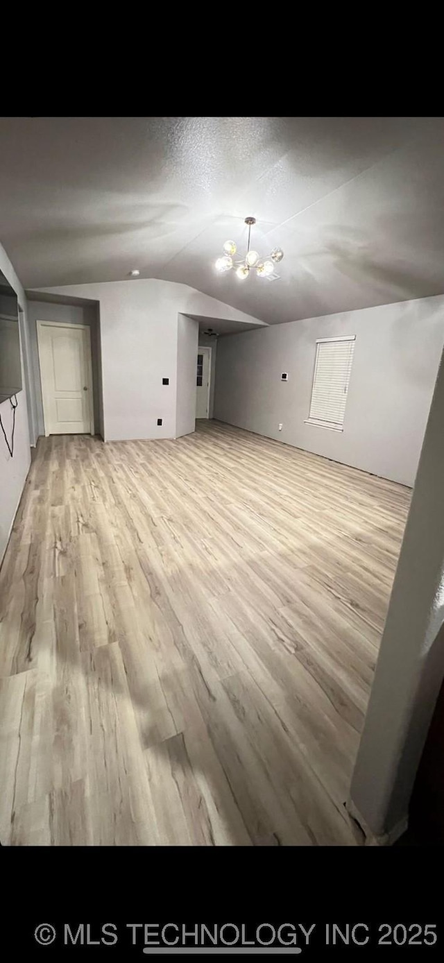 empty room featuring lofted ceiling, wood finished floors, and a textured ceiling