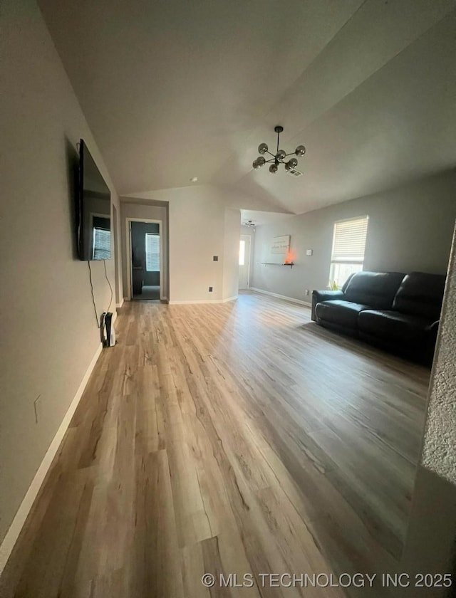 unfurnished living room featuring baseboards, lofted ceiling, and light wood-style flooring