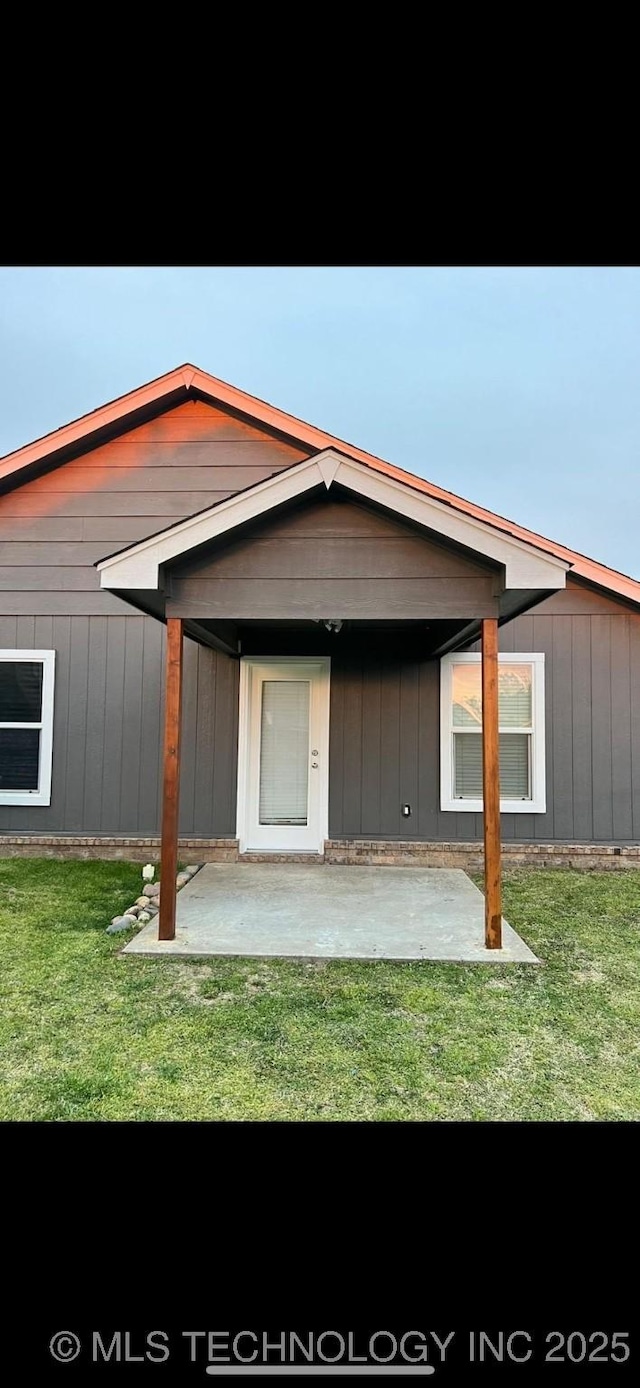 rear view of property featuring a patio area and a lawn