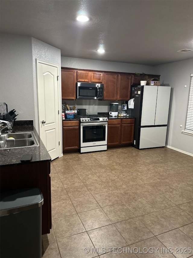 kitchen with visible vents, a sink, dark countertops, appliances with stainless steel finishes, and baseboards