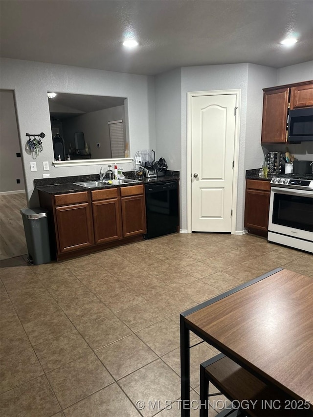 kitchen with dark countertops, black appliances, baseboards, and a sink