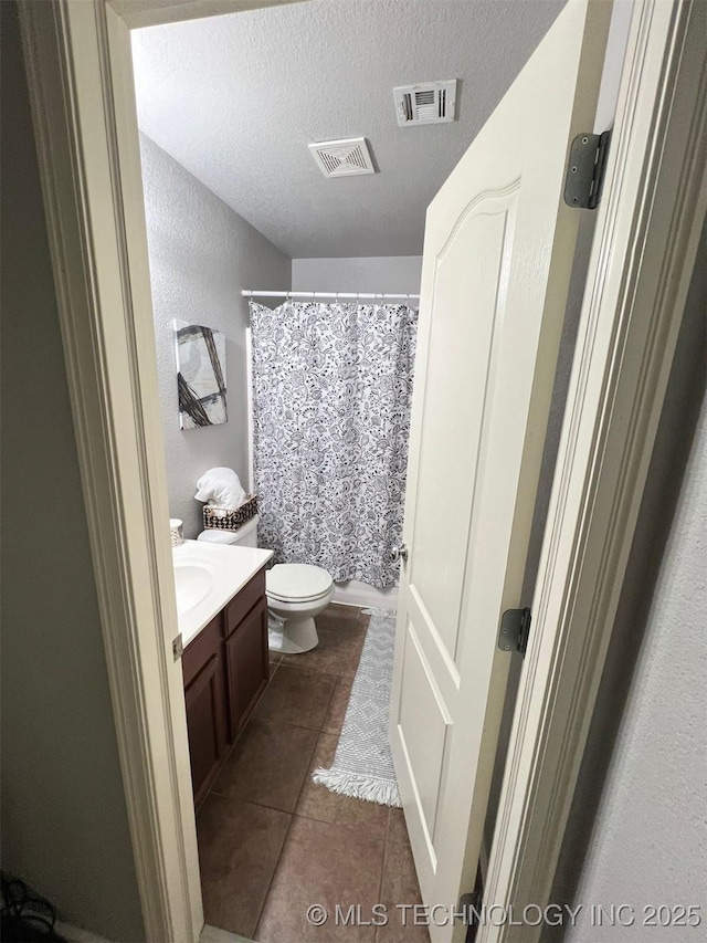 full bath featuring tile patterned flooring, visible vents, toilet, vanity, and a textured ceiling