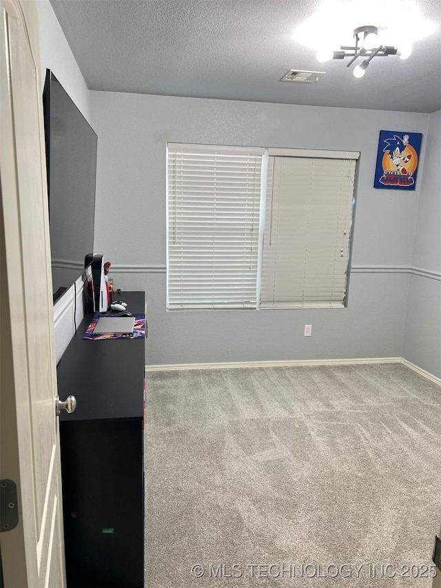 interior space featuring baseboards, visible vents, a textured ceiling, and carpet