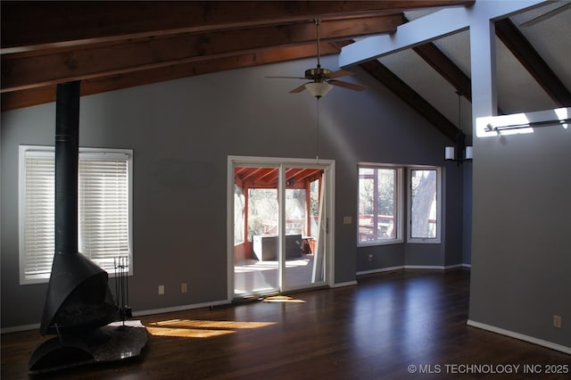 unfurnished living room featuring beam ceiling, wood finished floors, baseboards, ceiling fan, and a wood stove