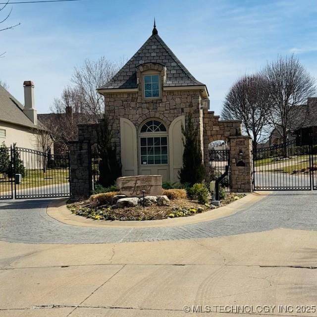 exterior space with a gate, fence, and stone siding