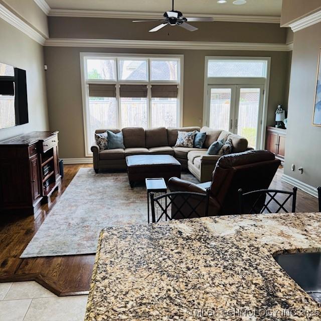 living area featuring a ceiling fan, baseboards, french doors, crown molding, and tile patterned floors