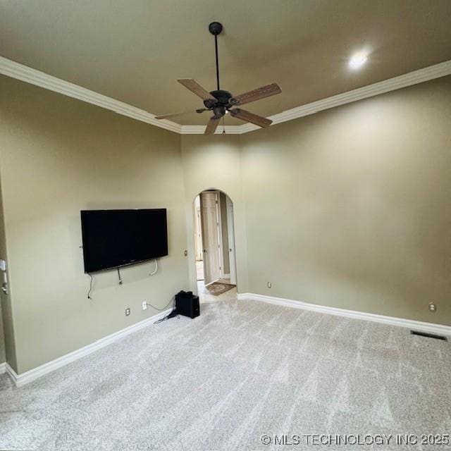 unfurnished living room with ornamental molding, a ceiling fan, arched walkways, carpet, and baseboards