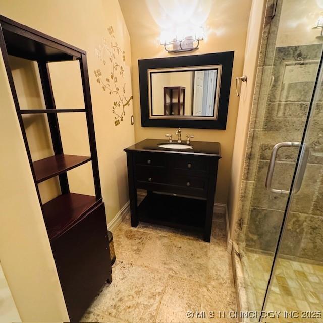 full bath featuring a stall shower, vanity, and baseboards