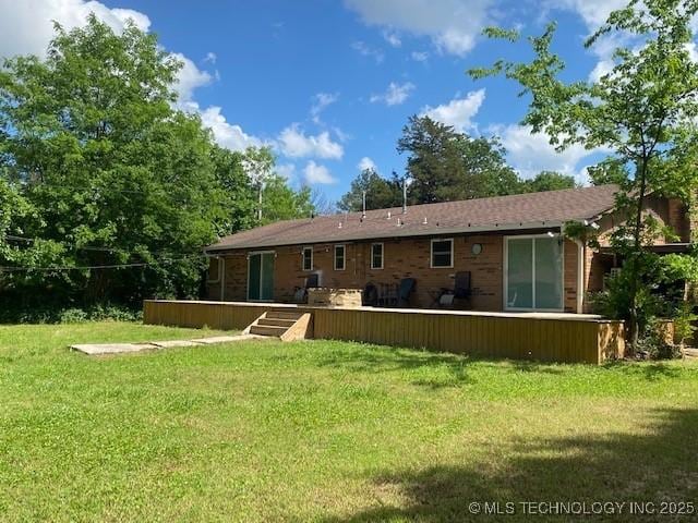 back of property featuring a wooden deck and a yard