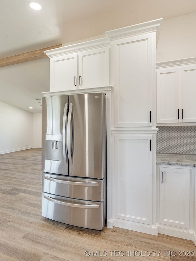 kitchen with light stone counters, light wood finished floors, white cabinets, stainless steel refrigerator with ice dispenser, and backsplash