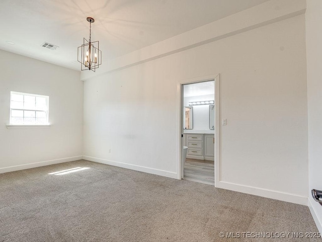 carpeted spare room featuring a chandelier, visible vents, and baseboards