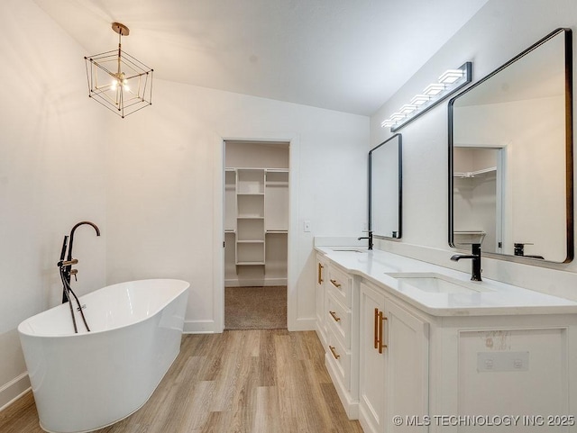 bathroom with a sink, a soaking tub, and a spacious closet
