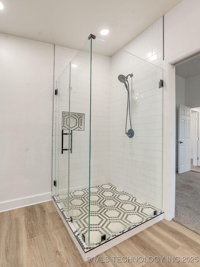 full bathroom featuring wood finished floors, a stall shower, and baseboards