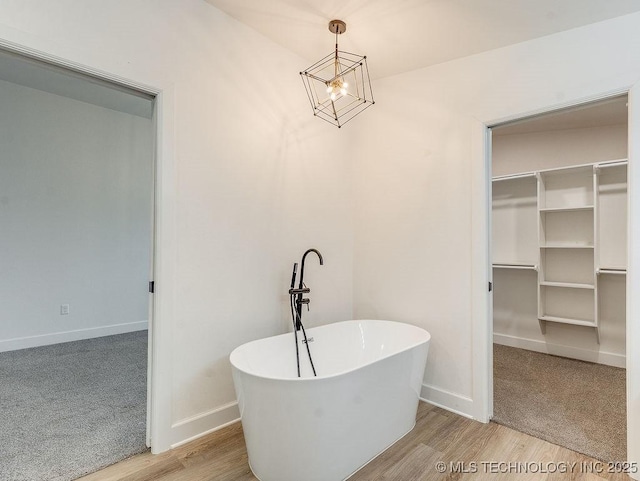 bathroom with wood finished floors, baseboards, and a freestanding tub