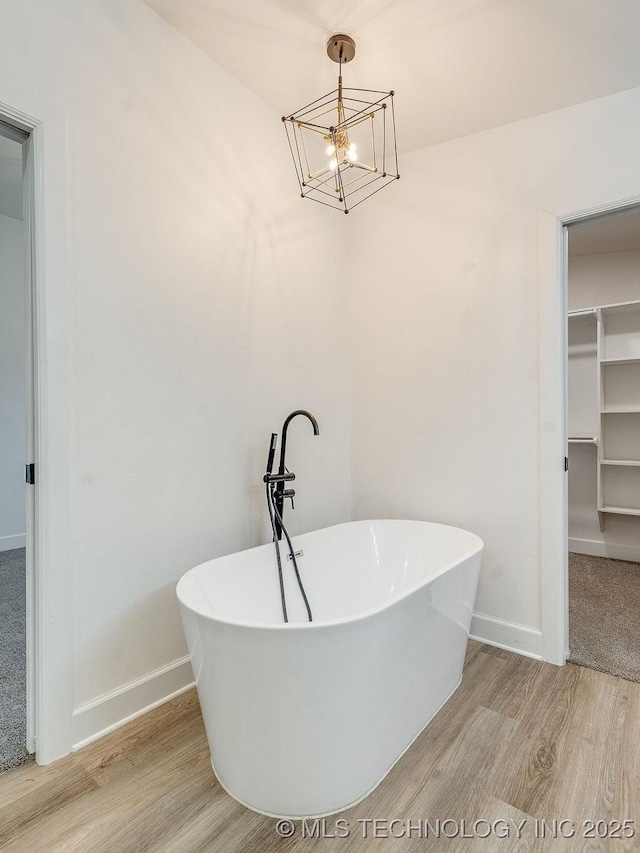 full bathroom featuring a freestanding tub, wood finished floors, and baseboards