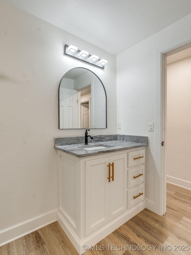 bathroom featuring vanity, baseboards, and wood finished floors