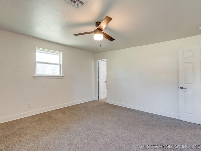 carpeted spare room with visible vents, baseboards, and ceiling fan