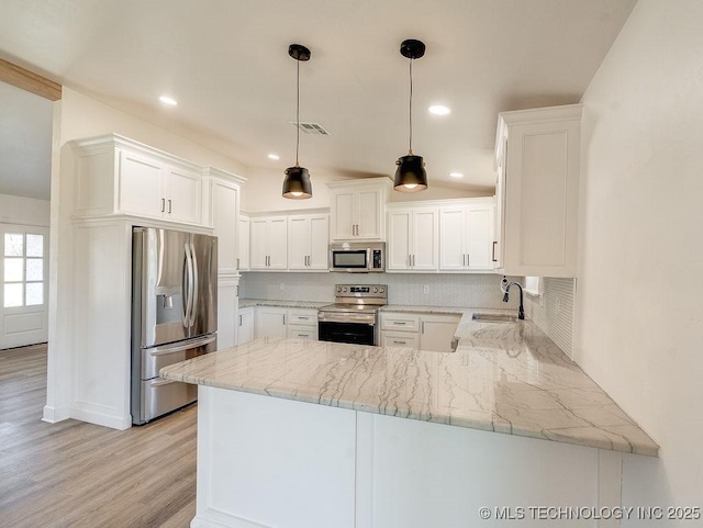 kitchen featuring visible vents, a peninsula, a sink, stainless steel appliances, and backsplash