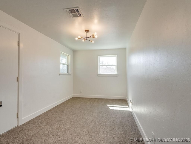 carpeted spare room featuring visible vents, plenty of natural light, baseboards, and an inviting chandelier