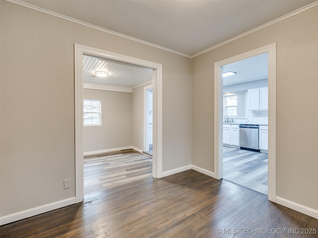 spare room with baseboards, dark wood-type flooring, a healthy amount of sunlight, and ornamental molding