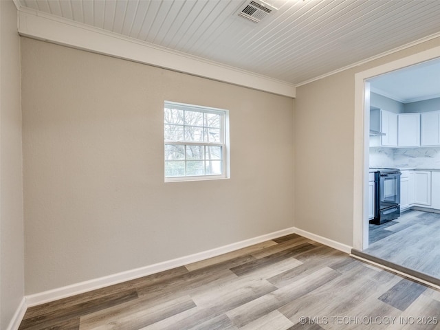 spare room with visible vents, crown molding, light wood-type flooring, and baseboards