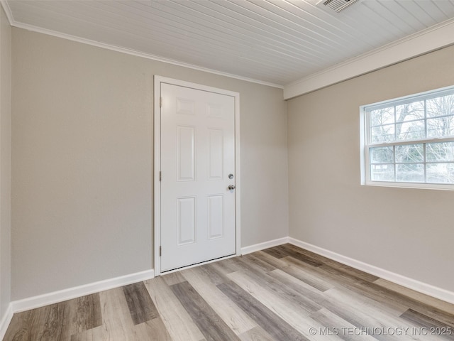 spare room featuring baseboards, wood finished floors, and crown molding