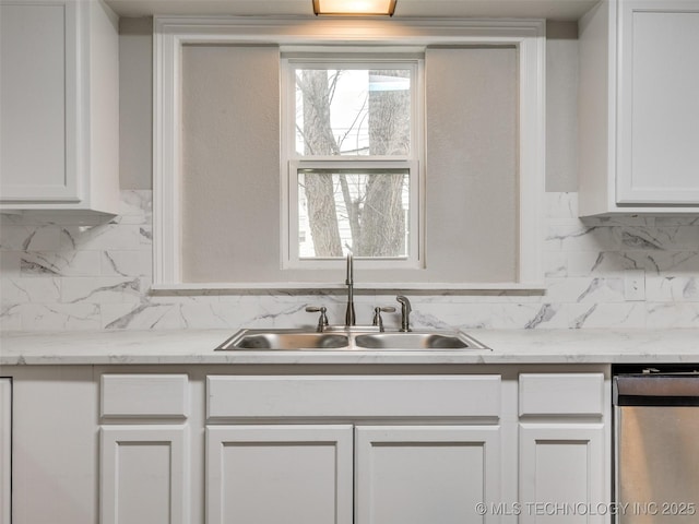 kitchen featuring stainless steel dishwasher, white cabinets, backsplash, and a sink