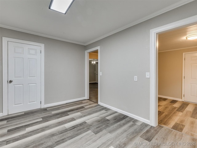 empty room with baseboards, crown molding, and light wood-style floors