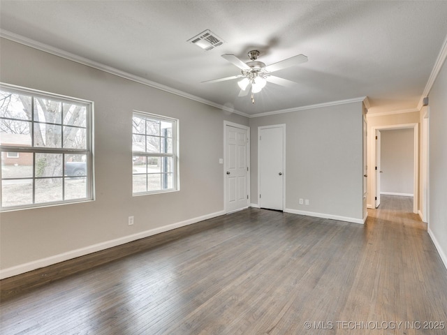 empty room featuring visible vents, baseboards, dark wood-style floors, and ornamental molding