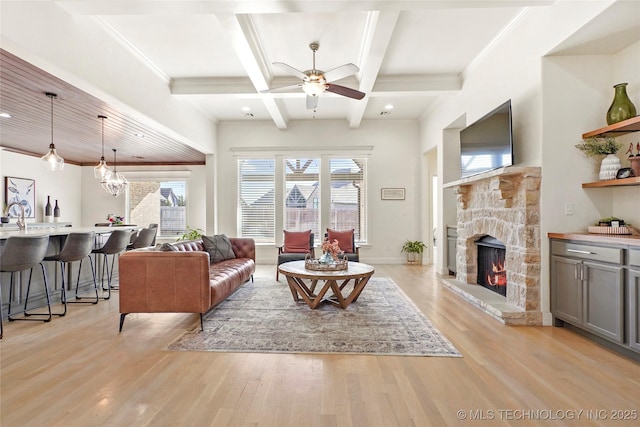 living room with beam ceiling, coffered ceiling, a fireplace, light wood finished floors, and ceiling fan